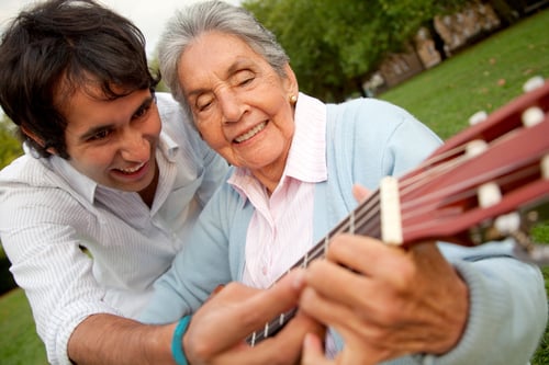 Grandson teaching her grandma how to play the guitar