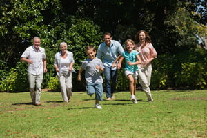 Happy multi generation family running towards camera in the park on sunny day