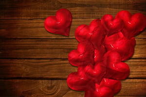 Red love hearts against overhead of wooden planks