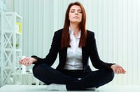 Young beautiful businesswoman meditates on the table in office
