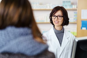 Young Female Pharmacist Talking to a Customer at the Counter Pleasantly.